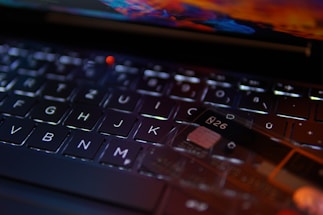 A close-up view of a keyboard with a focus on the keys. A transparent card with the text 'N26' is positioned on the keyboard, indicating a digital or banking theme. The lighting creates reflections and highlights that add a modern and technological feel.