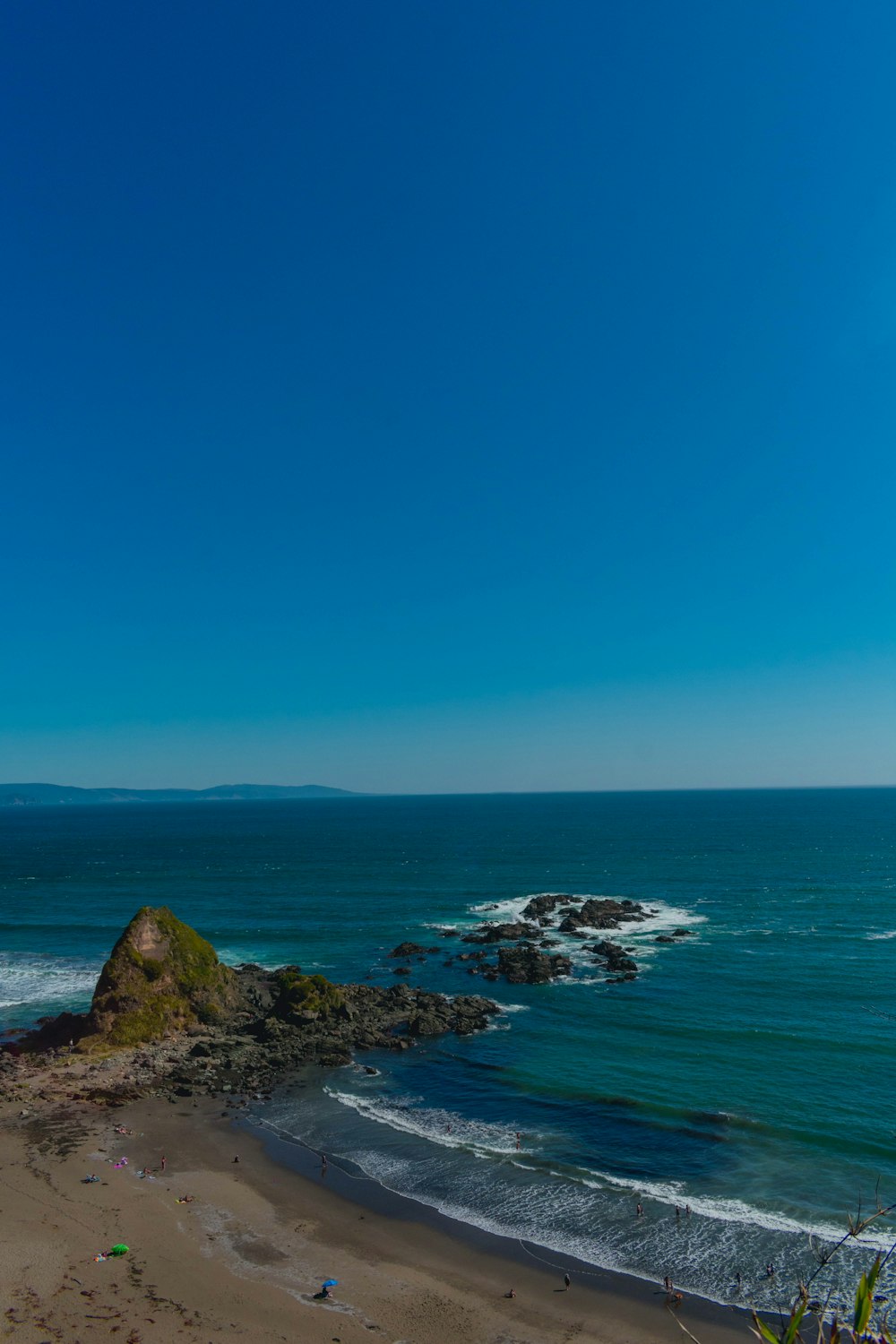 green and brown rock formation on sea under blue sky during daytime