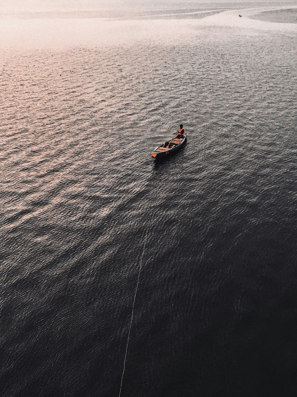 2 people riding on orange kayak on blue sea during daytime