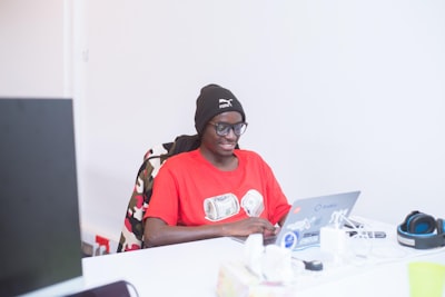 man in red crew neck t-shirt wearing black cap and black sunglasses rwanda teams background