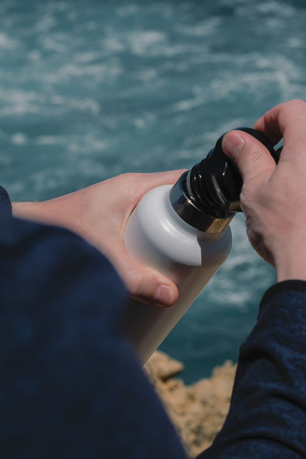 Persona sosteniendo una botella blanca y negra