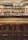 A dimly lit bar with shelves filled with a variety of liquor bottles. The bar features three red cushioned stools and is adorned with warm wall lamps on either side, adding a cozy and vintage feel. The arching stone ceiling adds to the rustic ambiance.