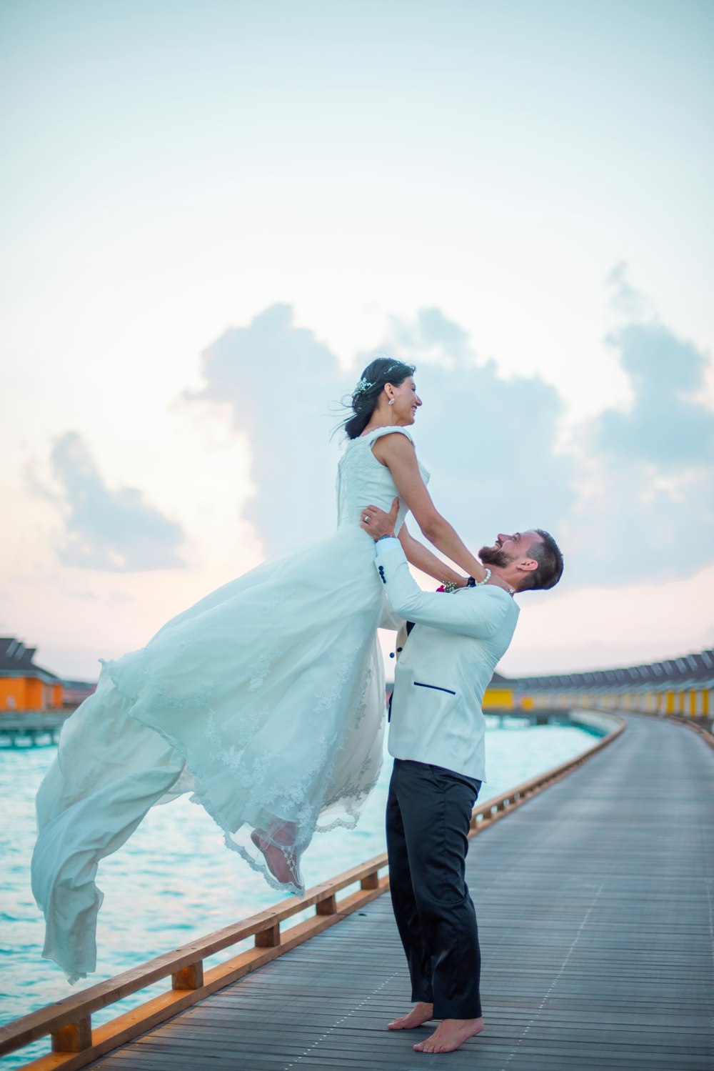 man in white dress shirt and blue denim jeans kissing woman in white wedding dress on near on near on