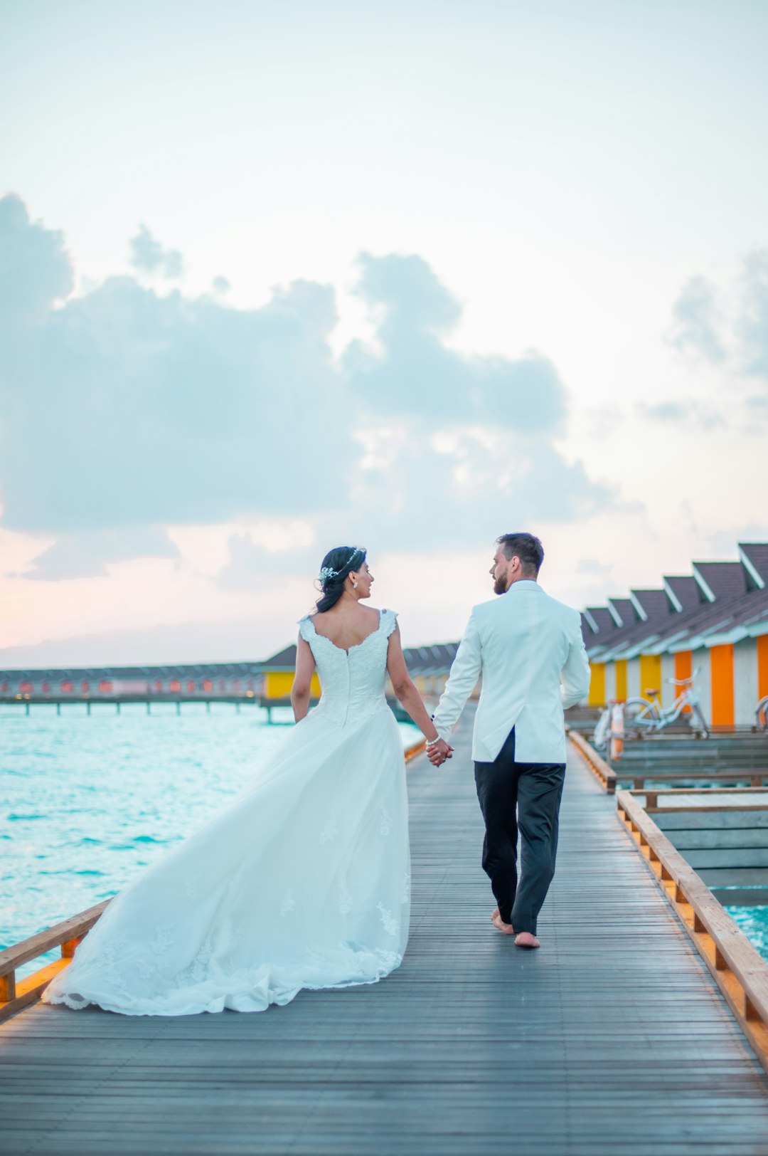 man and woman holding hands while walking on wooden dock during daytime