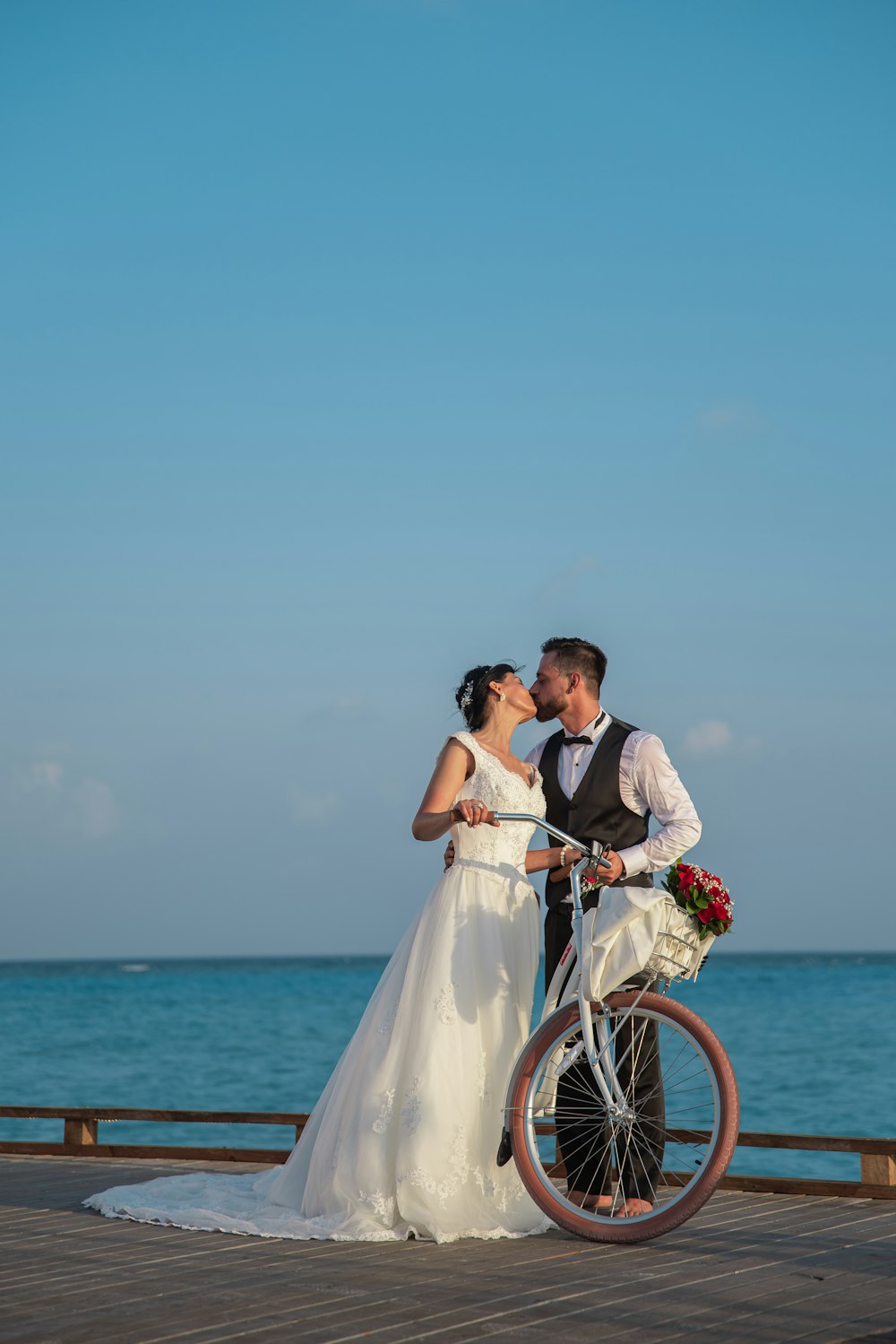 man and woman kissing on bicycle near sea during daytime