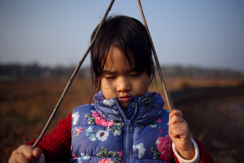 a little girl holding a stick in her hands