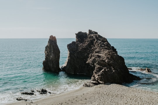 brown rock formation on sea during daytime in Liguria Italy