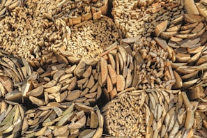 A large stack of cut and split firewood arranged in a tightly packed pattern. The logs are arranged in circular and grid-like formations, creating a visually interesting texture with different shades of brown and beige.