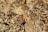 A large stack of cut and split firewood arranged in a tightly packed pattern. The logs are arranged in circular and grid-like formations, creating a visually interesting texture with different shades of brown and beige.