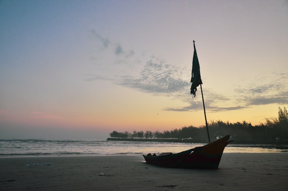 red boat on beach during sunset