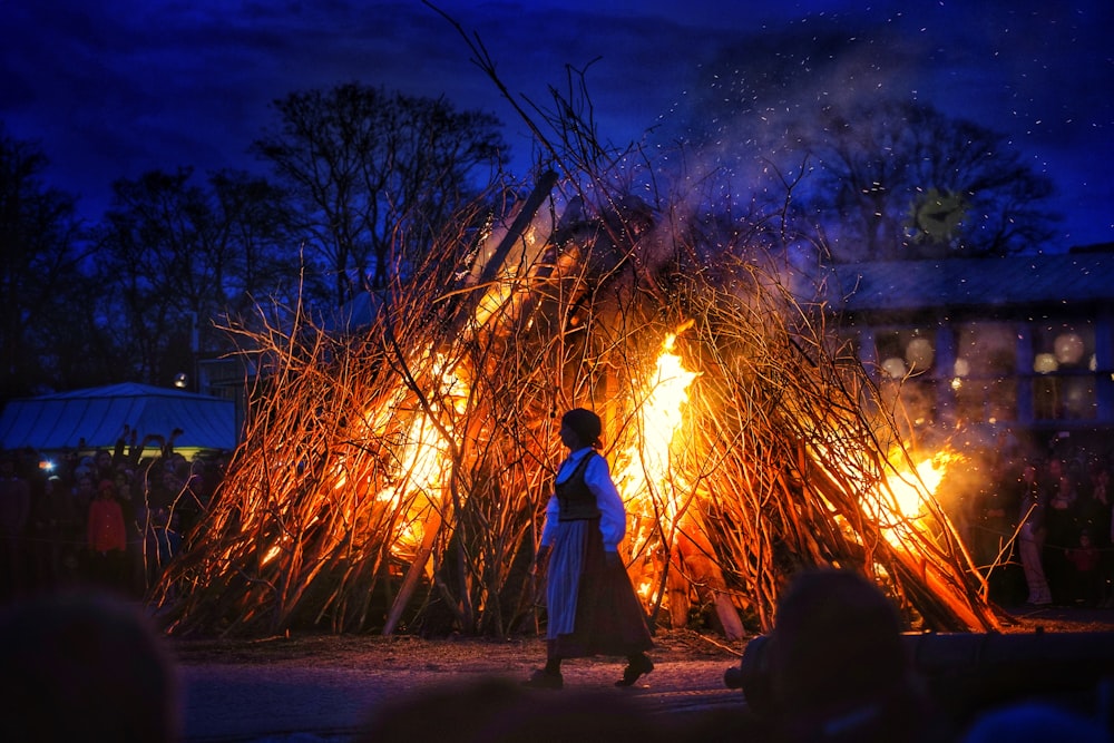 man in white robe standing near bonfire during night time