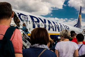 Passengers near a jet under a cloudy sky
