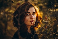 Golden hour portrait of a woman surrounded by autumn leaves, expressive and serene.