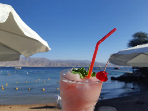 Colorful tropical cocktail with fresh fruit garnish on a sunny beach table.