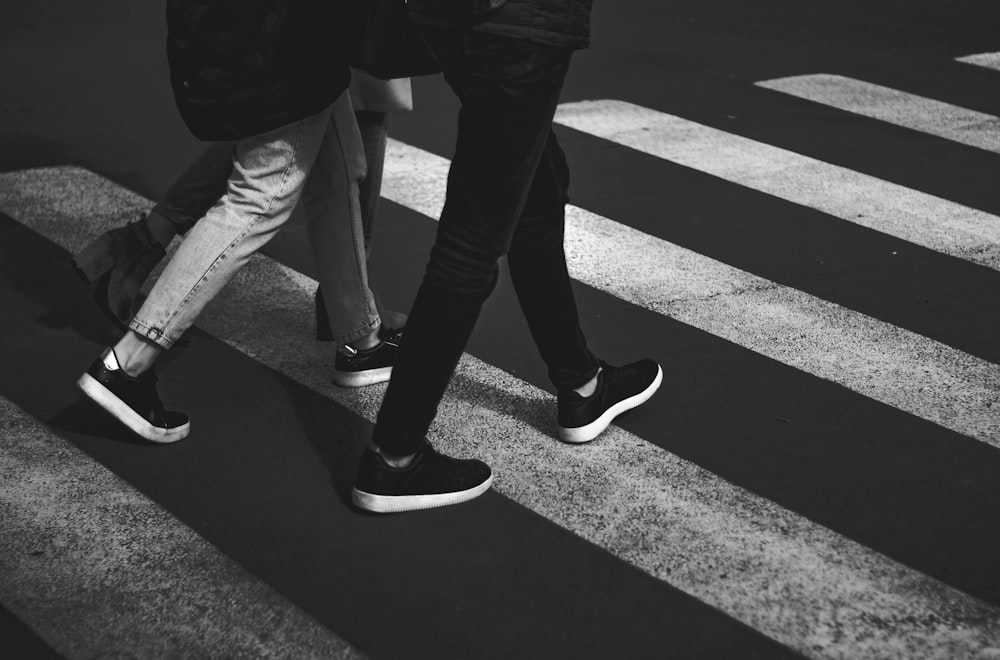 person in black pants and white sneakers standing on pedestrian lane