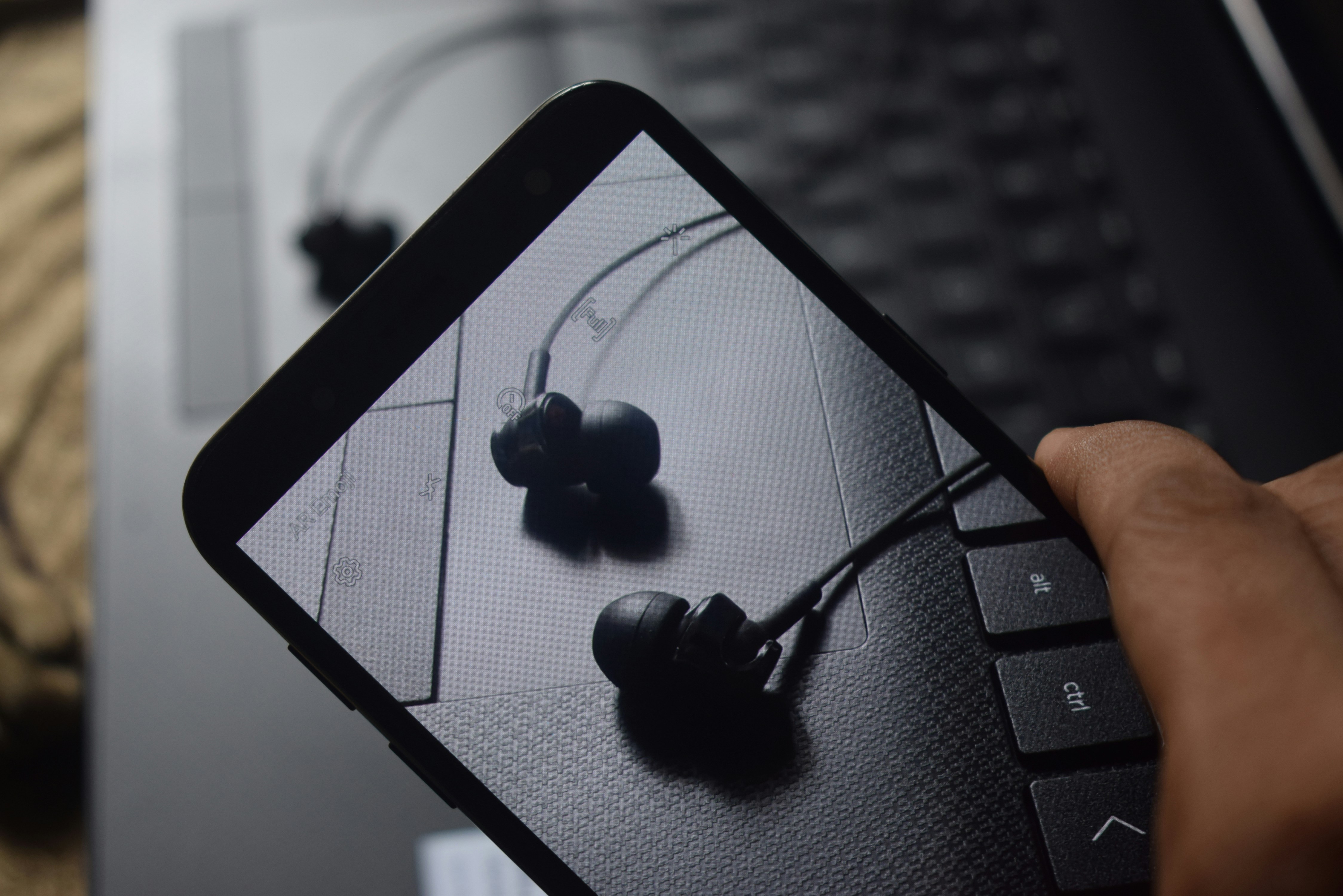 A pair of over-ear headphones plugged into a smartphone displaying a music app, with abstract sound waves illustrating audio technology.