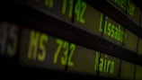 Departure board displaying flight information with destinations such as Lissabon and Kairo in bright green digital text over a dark background.
