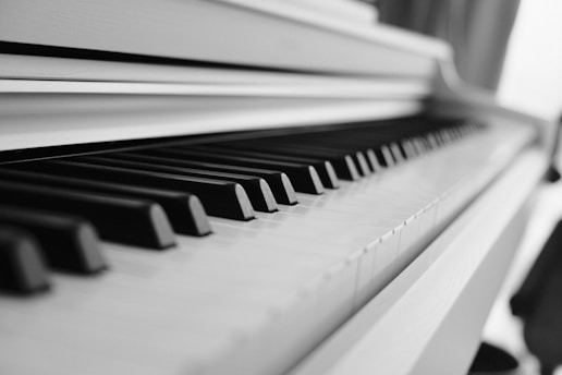 A close-up view of piano keys, focusing on the alternating pattern of black and white keys. The perspective creates a sense of depth and visual rhythm.