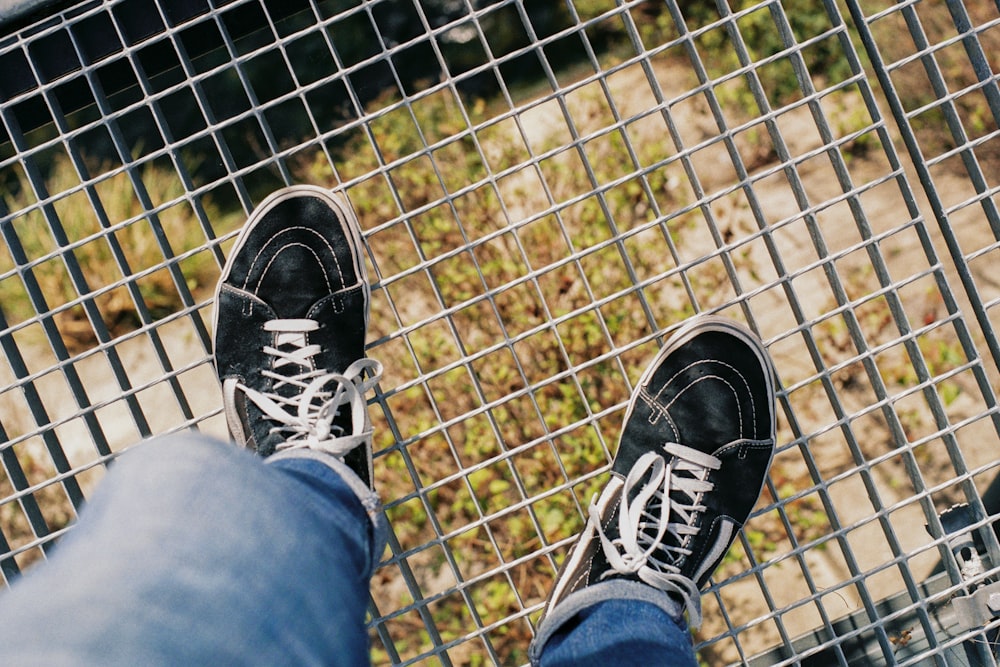person in blue denim jeans and black and white sneakers