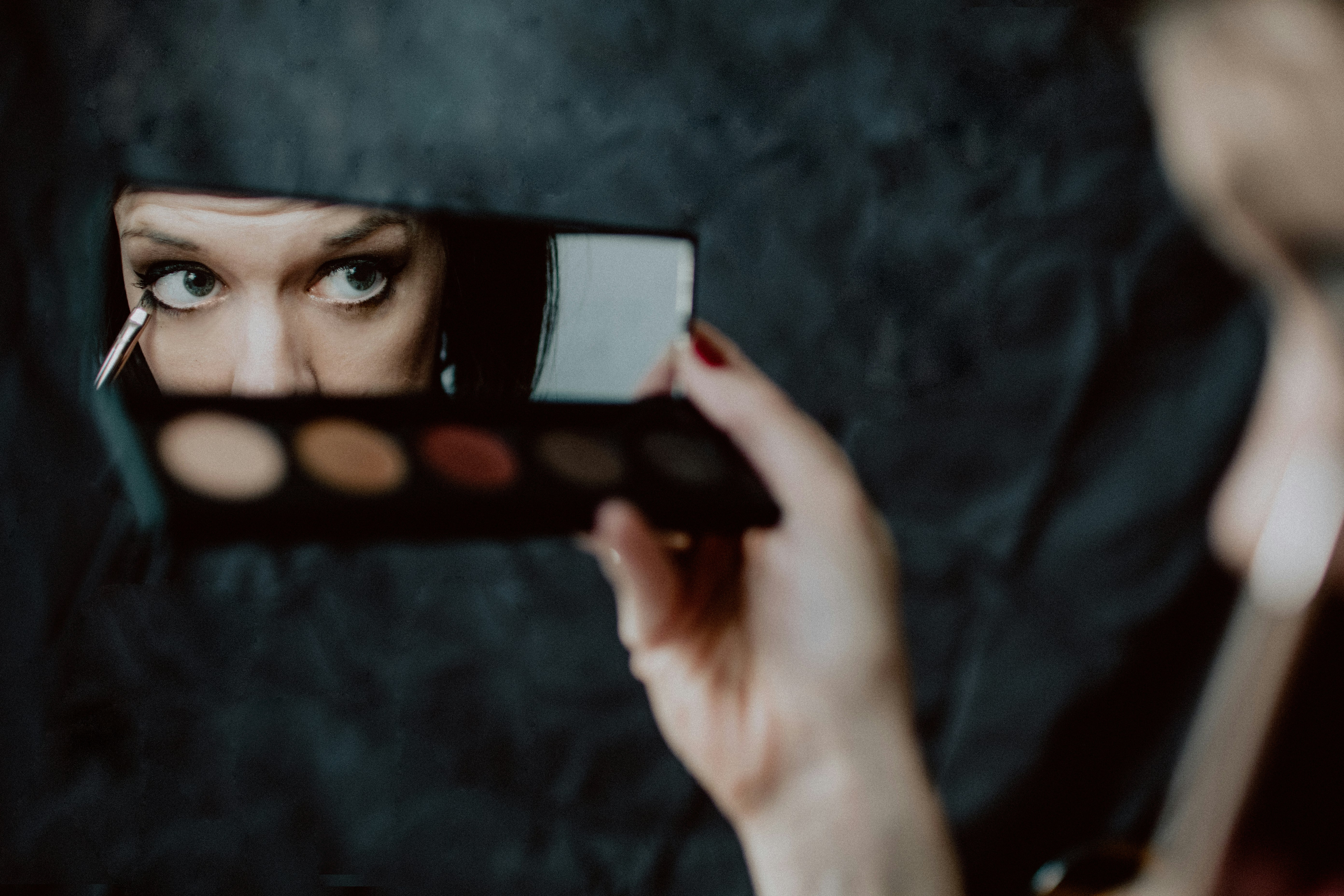 Woman applying eyeshadow in a mirror