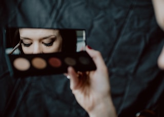 woman holding black and silver make up palette