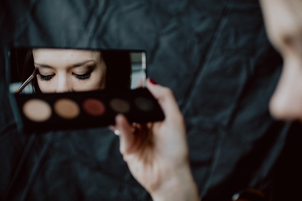 woman holding black and silver make up palette