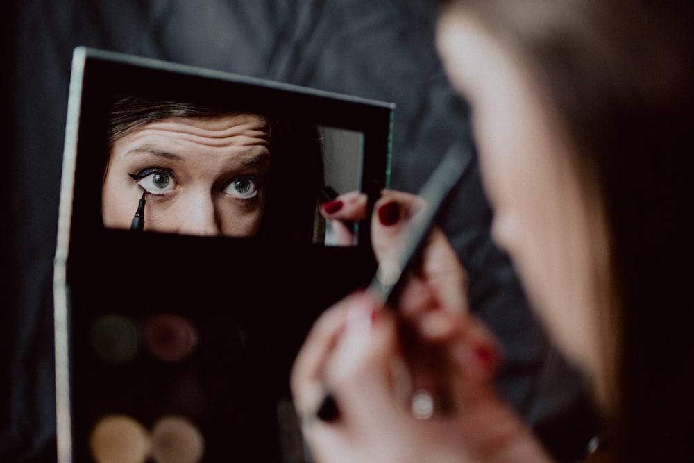 黒い額縁の鏡を持つ女性