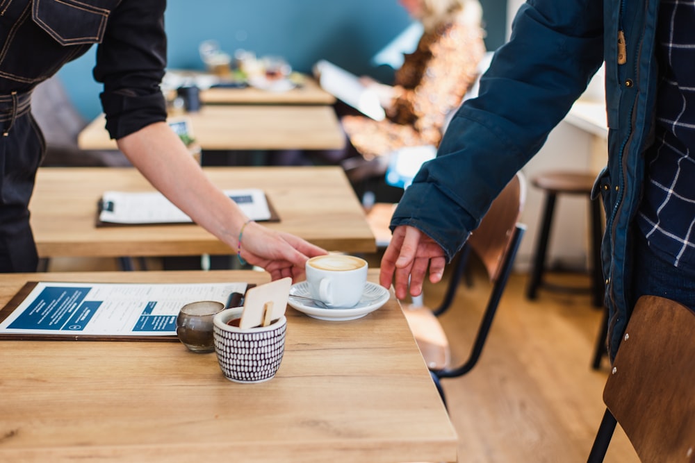 person pouring white liquid on white ceramic teacup