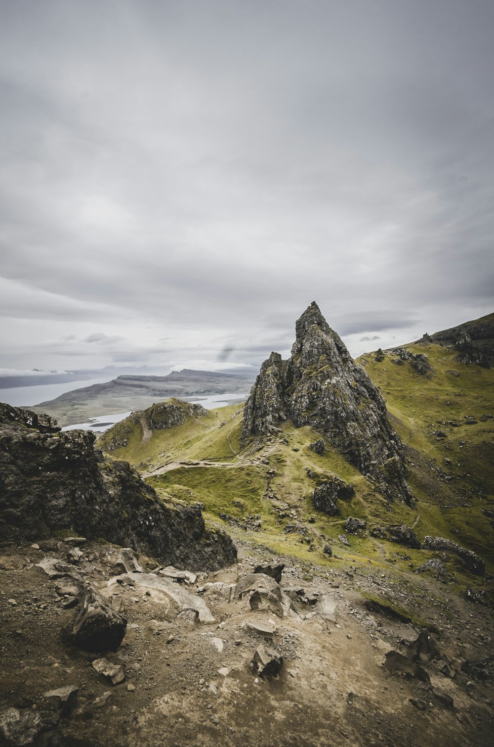 a rocky mountain with grass and rocks in the foreground