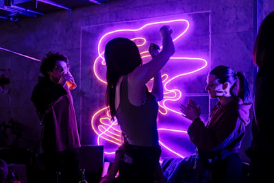A group of friends laughing together under purple neon signs.