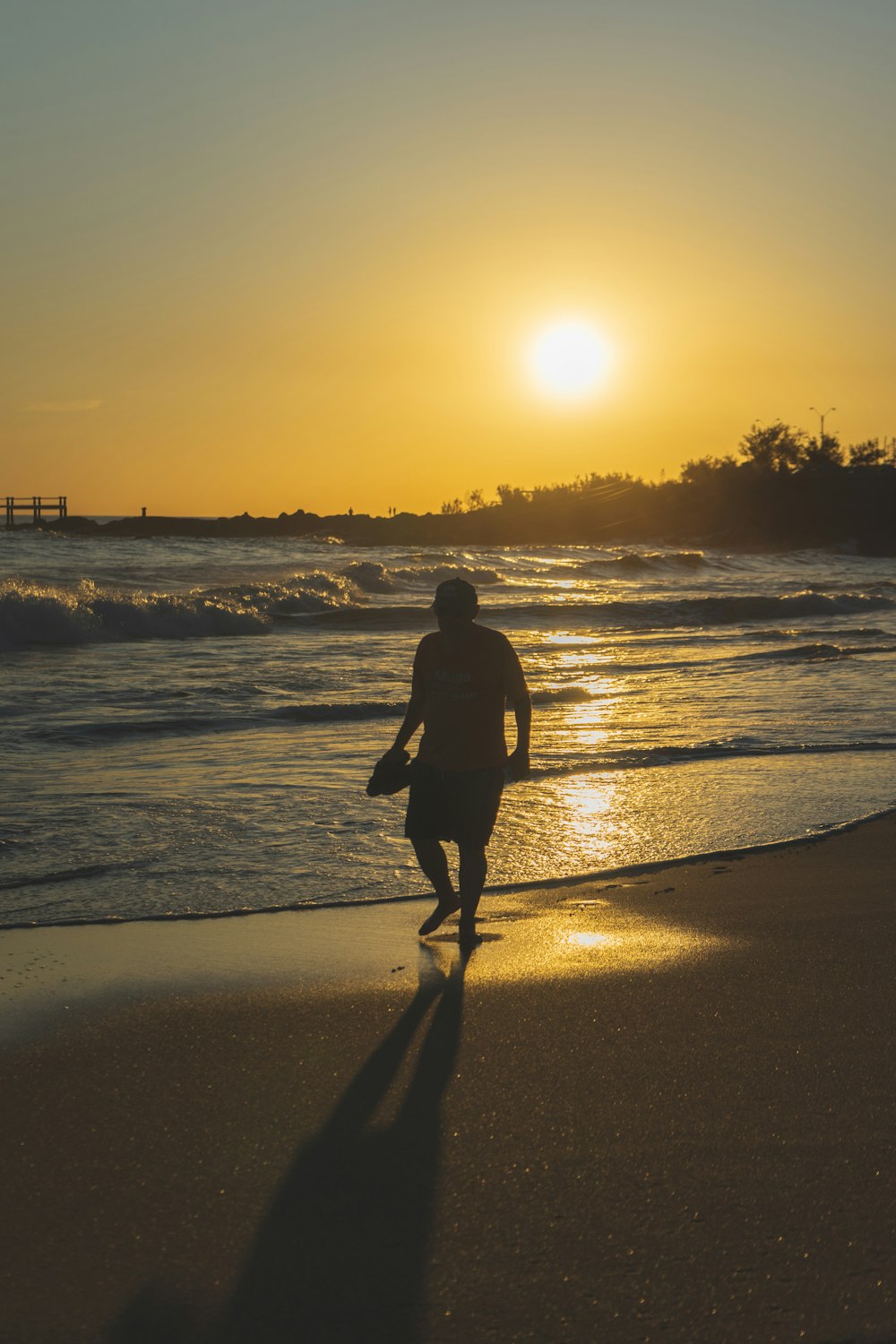 silhouette of man walking on beach during sunset