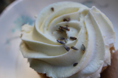 A close-up of a delicate cupcake topped with pastel flower decorations made from natural dyes.