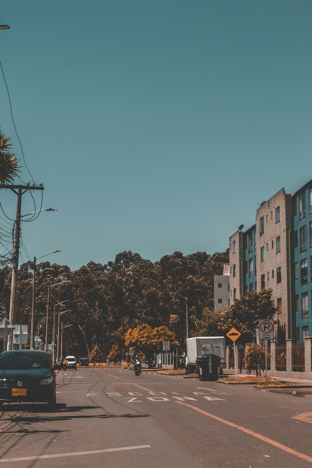 cars parked on side of the road near high rise buildings during daytime