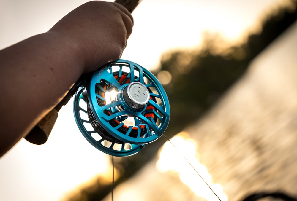 person holding blue and black round plastic