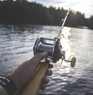 person holding black and silver fishing reel