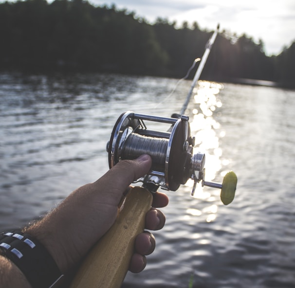 person holding black and silver fishing reel