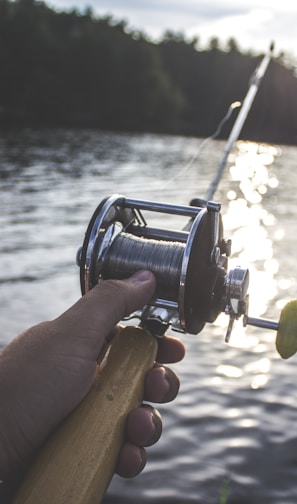 person holding black and silver fishing reel