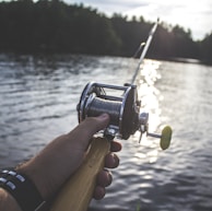 person holding black and silver fishing reel