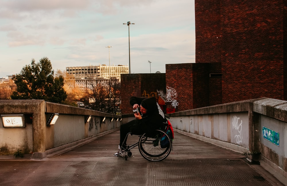 man in black jacket riding bicycle on gray concrete bridge during daytime