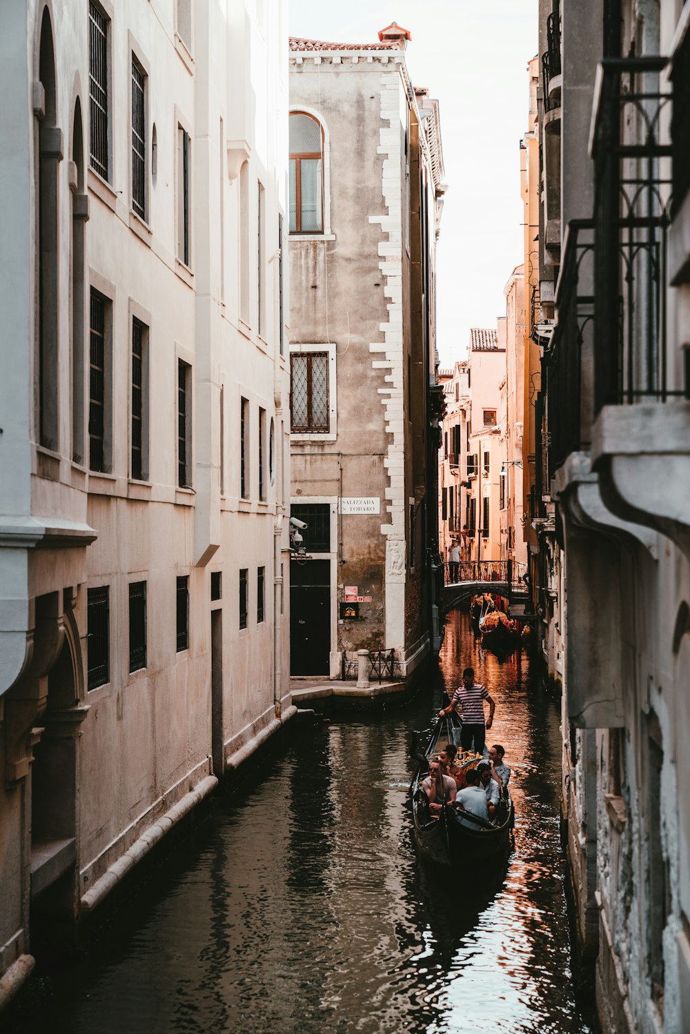 people riding on boat on river between concrete buildings during daytime