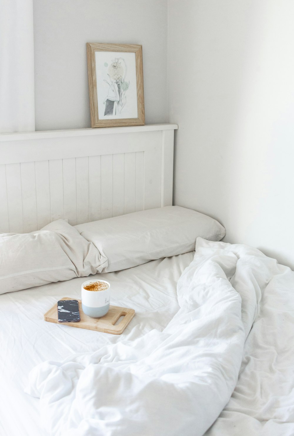 white ceramic mug on white bed
