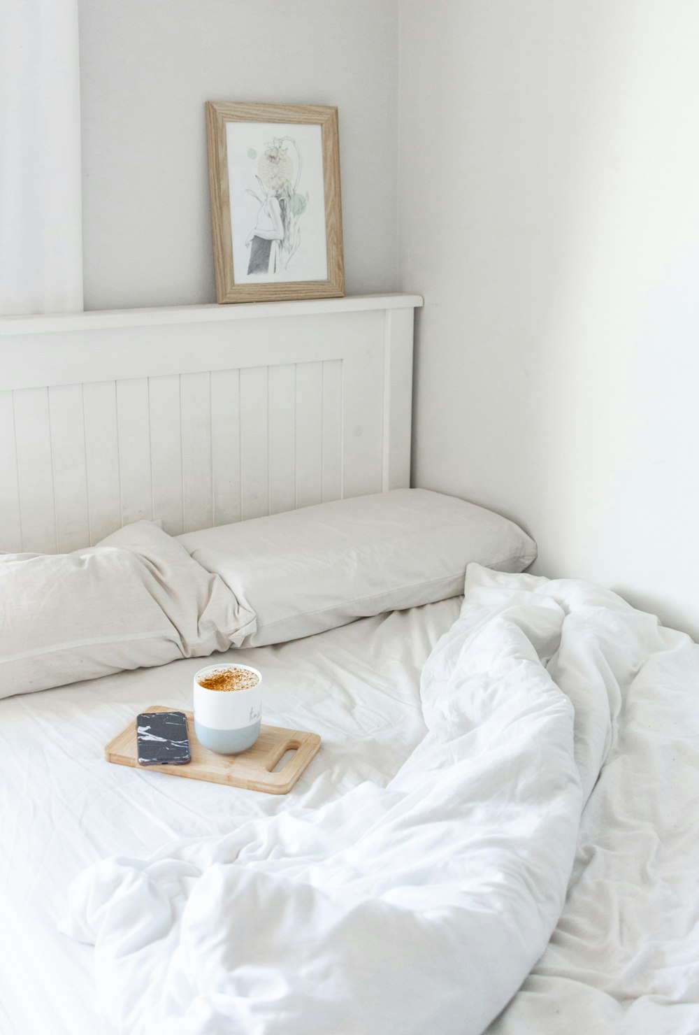 Taza de cerámica blanca sobre cama blanca