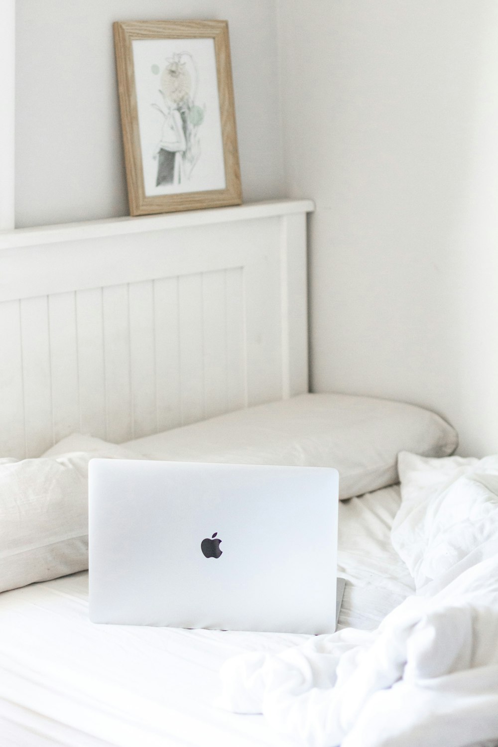 MacBook argenté sur lit blanc