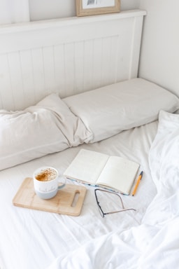 A cozy morning scene with a cup of coffee on a wooden table beside a handwritten journal and a soft blanket.