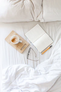 A cozy scene with a notebook, pen, and a cup of coffee beside a softly lit lamp.