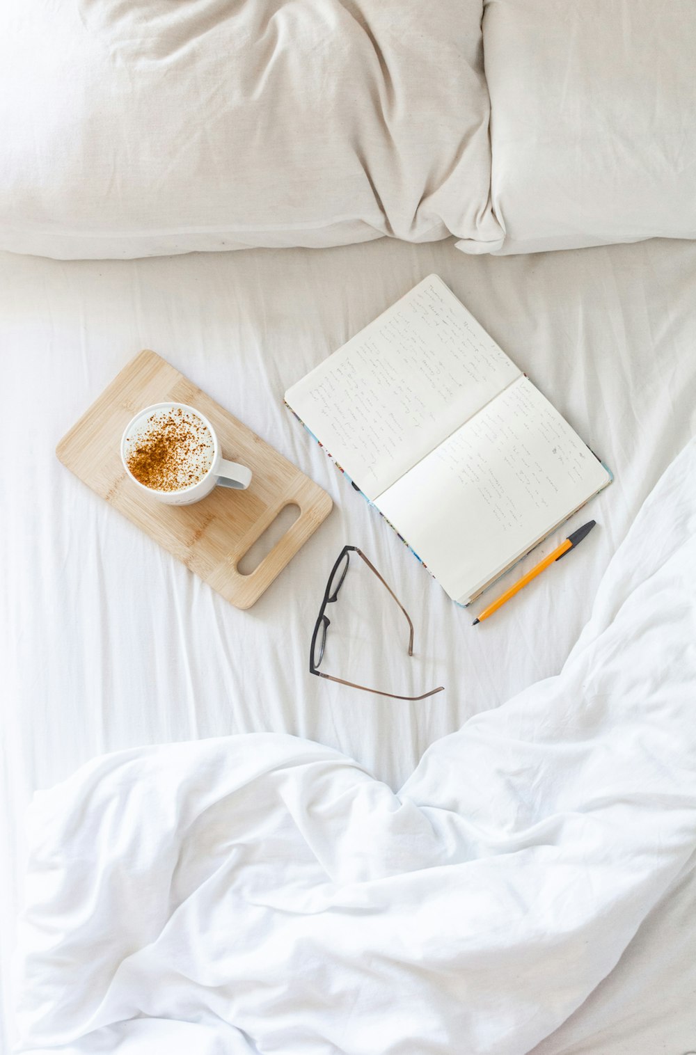 white book beside brown ceramic mug on white textile