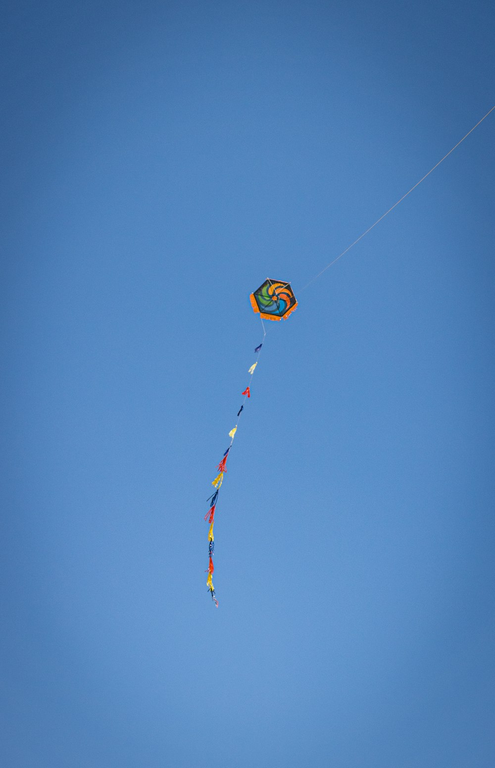 yellow blue and red kite flying under blue sky during daytime