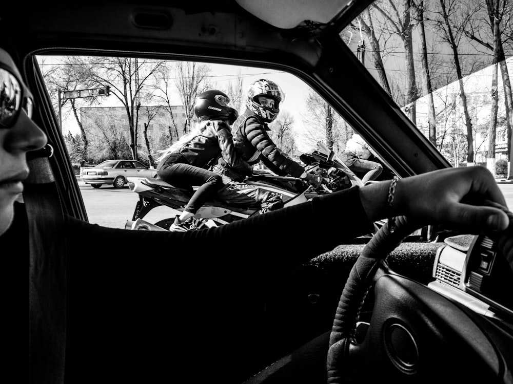 grayscale photo of man driving car