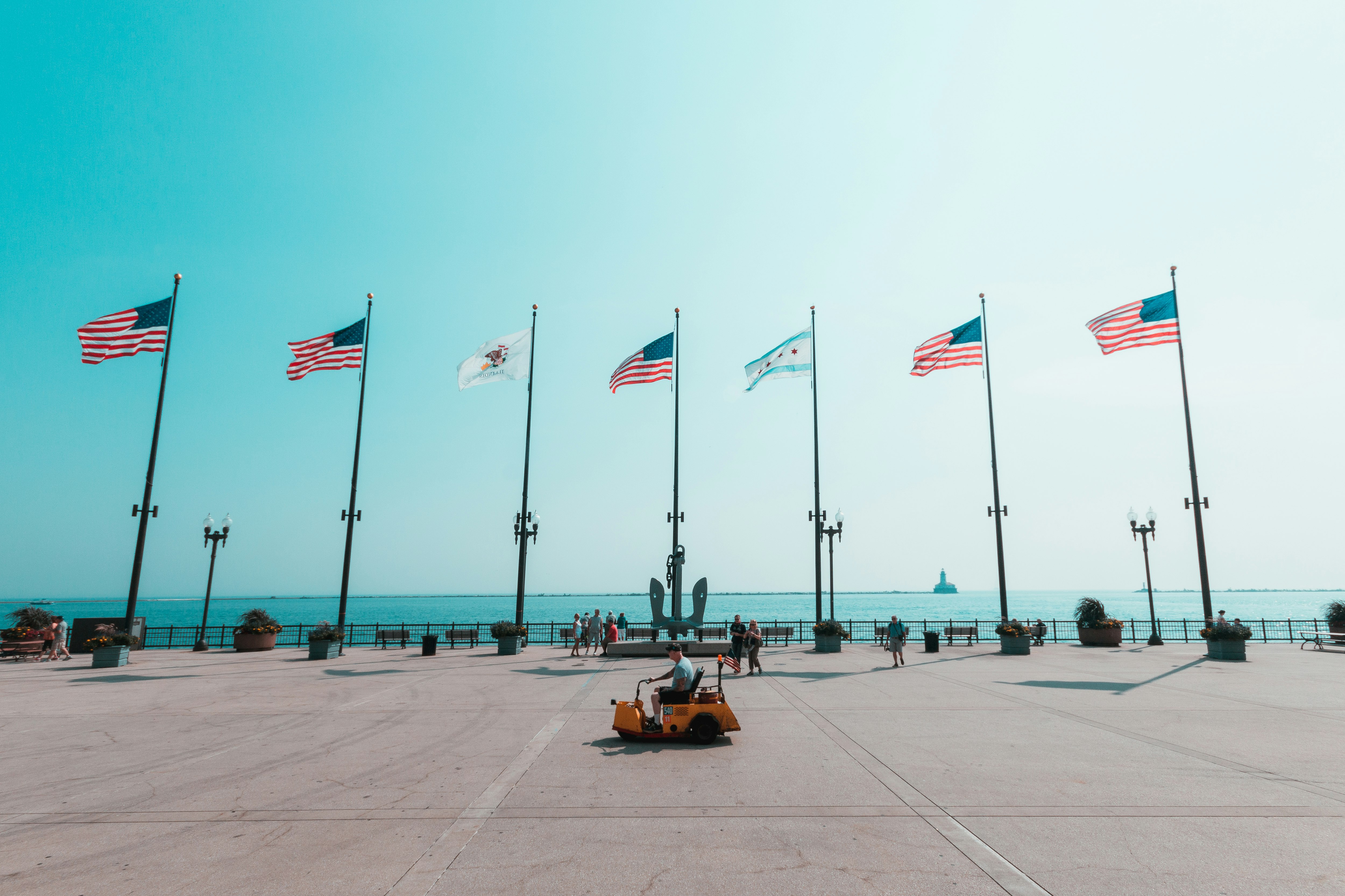 people on beach shore with flags on the side during daytime