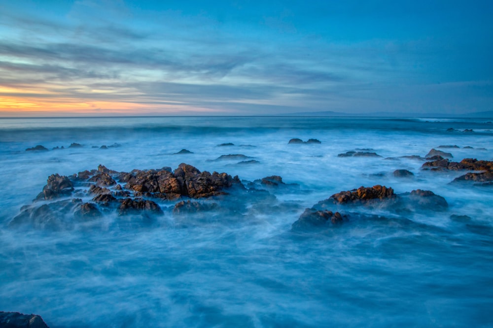 brown rock formation on sea under blue sky during daytime